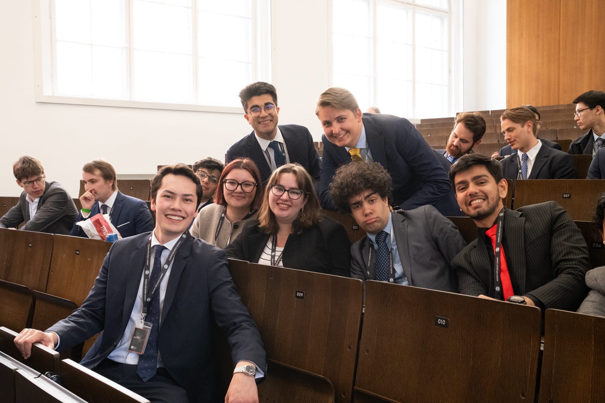 Delegates smiling in a lecture hall at the Munich Diplomacy Summit