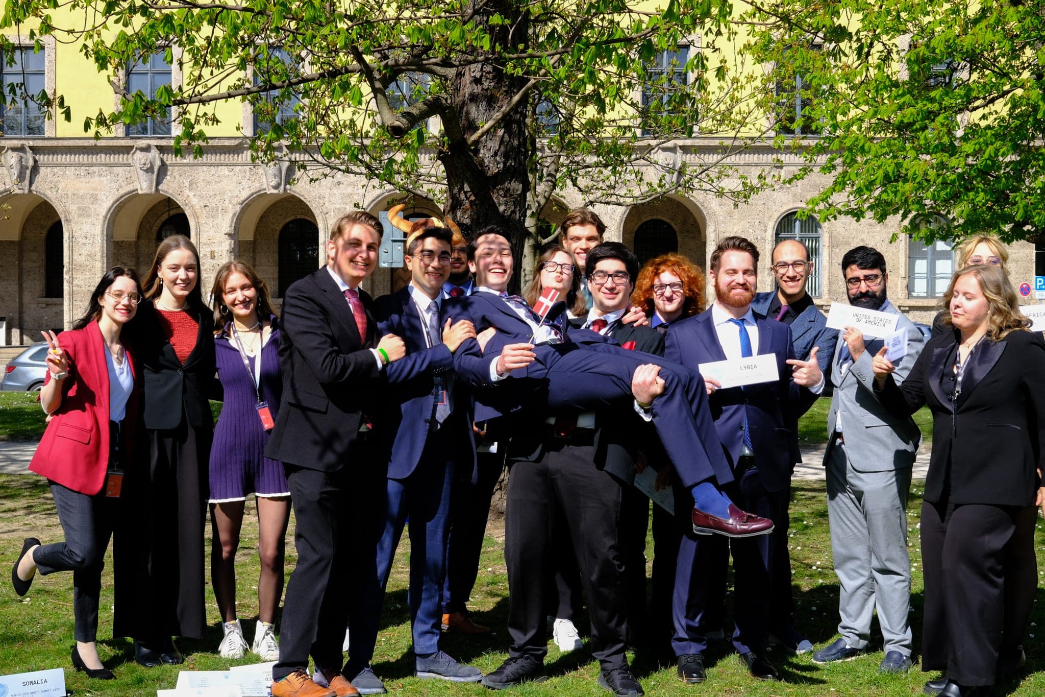 Delegates in suits celebrating outside at the Munich Diplomacy Summit